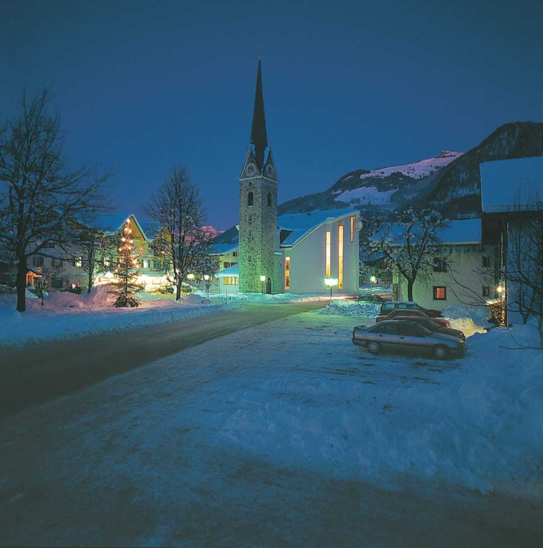 Verschneiter Ortskern Maishofen mit Kirche und Lichtern bei Nacht, Winterurlaub Zell am See