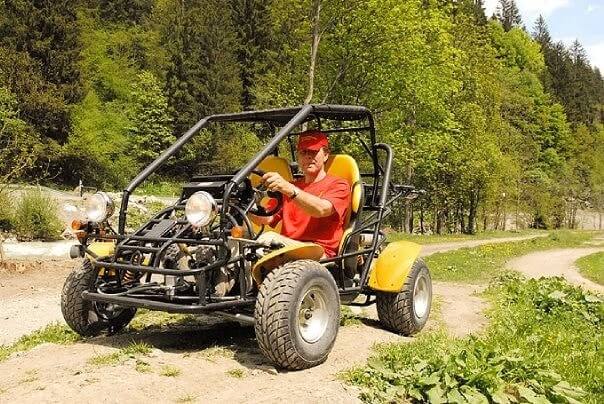 Мужчина управляет багги на внедорожнике в сельской местности недалеко от Целль-ам-Зе во время семейного отдыха в Schloss Saalhof