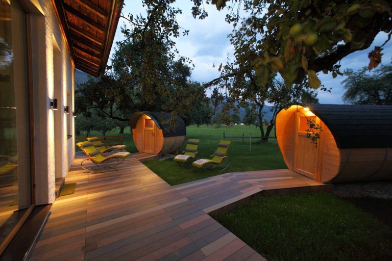 Освещенные бочкообразные сауны с лежаками в саду Schloss Saalhof, фермерский отдых Целль-ам-Зее
