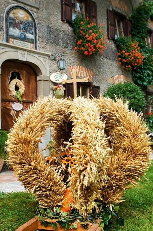 Große Getreidekrone vor dem Schloss Saalhof, Blumenschmuck an Fenstern, Bauernhofurlaub Zell am See